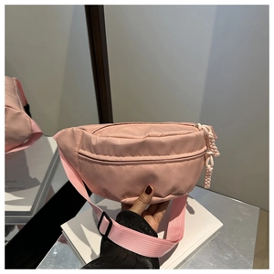 Detail of pink waterproof nylon chest bag with woven zipper pull and adjustable strap