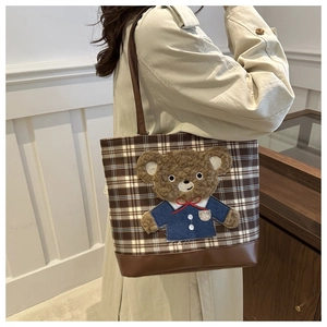 Detail of checkered tote bag with brown leather trim and cute 3D plush bear mascot
