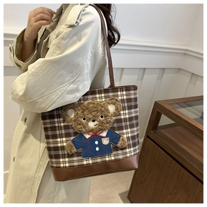 Detail of coffee plaid tote bag featuring a 3D plush bear and reinforced leather base