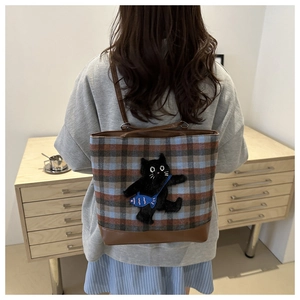 Close-up of retro plaid tote bag with 3D black cat patch and brown leather handles