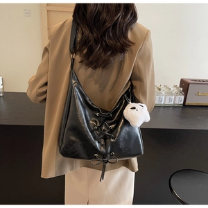 Detail of black PU leather tote bag with lace-up bow and plush ghost charm accessory