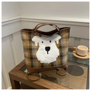Detail of the plaid tote bag featuring a cute white furry dog patch and leather straps