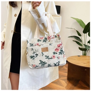 Detalle de la bolsa de almuerzo de lona floral con rosas y etiqueta de cuero marrón