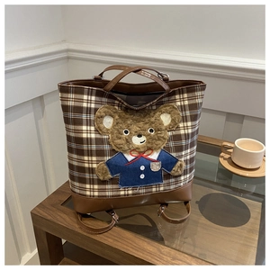Detailed view of checkered canvas tote bag featuring a cute 3D plush teddy bear charm