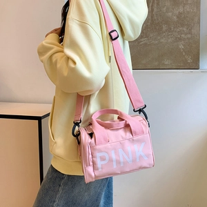 Minimalist pink nylon cylinder crossbody bag with PINK lettering and adjustable wide strap