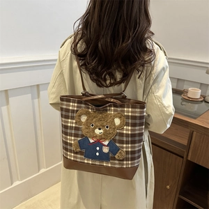 Brown plaid backpack with plush bear charm worn by model in minimalist setting