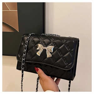 Detail of black quilted leather chain bag featuring a gold bow metal clasp and strap