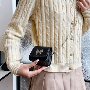 Mini black chain saddle bag with silver butterfly accent on a crossbody model