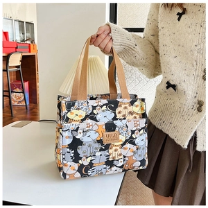 Detalle de una bolsa de lona para el almuerzo con estampados de gatos y logo de cuero
