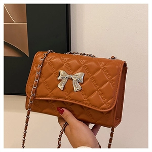 Detailed macro view of the brown quilted leather texture and silver bow buckle on bag