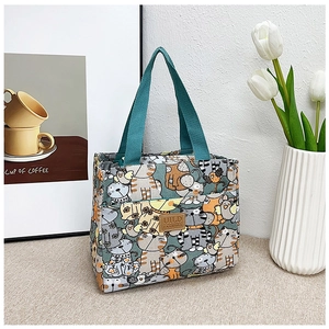 Detalle de bolsa de lona para almuerzo con estampado de gatos y asas verdes fuertes