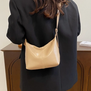 Beige crescent shoulder bag in glossy leather with elegant center stitching detail