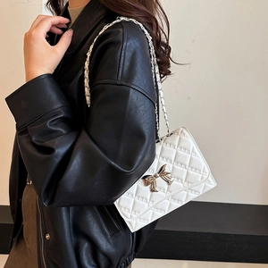 White quilted crossbody bag with silver bow accent and metal chain strap for women