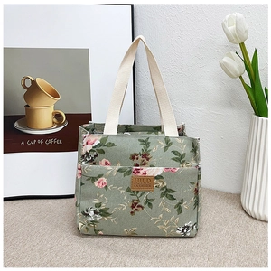 Detalle de la bolsa de almuerzo de lona floral con parche de cuero y asas reforzadas