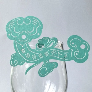 Macro view of green Ruyi-shaped paper wine glass decorative card with cutout text