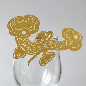 Detail of golden hollow-out wine glass card with traditional cloud pattern and chinese text