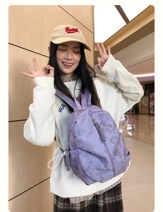 Detail of lavender nylon backpack with teddy bear print worn by a model in casual setting