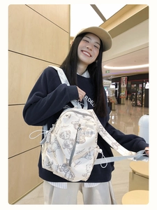 Detail of the white backpack featuring brown bear prints and Vamtac graphic branding