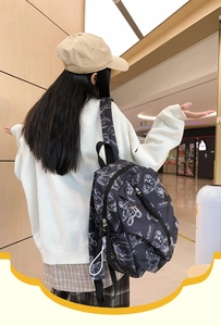 Detail view of black Vamtac backpack with white bear pattern and dual zipper closure
