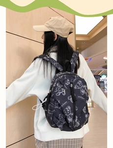 Close-up of lightweight black backpack featuring white teddy bear prints on durable fabric