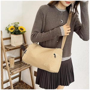 Dettaglio della tasca laterale con zip e logo metallico sulla borsa a tracolla kaki