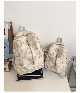 Close-up of beige school backpacks with bear print and sturdy gray woven zippers