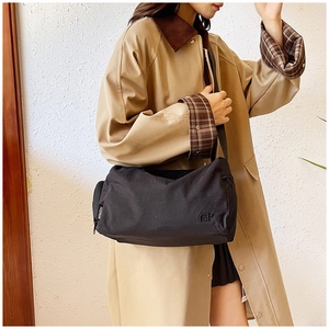 Dettaglio borsa a tracolla nera leggera con etichetta fashion e chiusura a cerniera lampo