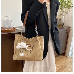 Détail du cabas en toile avec lanières en cuir marron, chaîne et pendentif nuage
