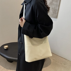Minimalist cream textured tote bag for women shown with black trench coat in a stylish pose