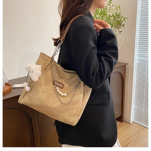 Grand sac fourre-tout kaki avec chaîne épaisse et breloque perle sur un blazer noir