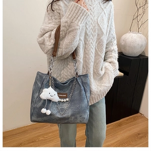 Détail du sac bandoulière en denim avec bandoulière cuir et chaîne et charm nuage doux