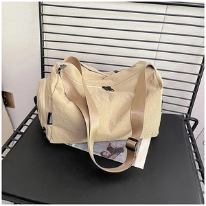Dettaglio della tracolla regolabile e dell'etichetta sulla borsa da viaggio beige