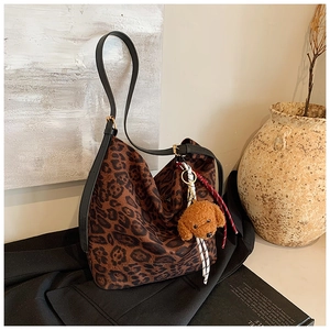 Close-up of leopard print tote bag featuring black leather straps and plush puppy charm
