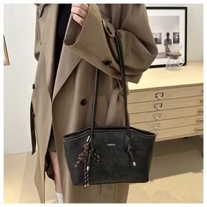 Dettaglio della grande borsa tote grigia con stampa fashion e ciondolo a nodo su un trench