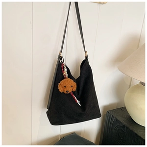 Detail of a black large-capacity shoulder tote bag with a cute brown teddy dog pendant