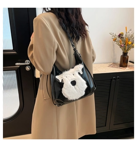 Close-up of a black leather tote bag featuring a cute white plush schnauzer dog design
