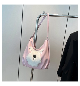 Detail of pink faux leather crescent bag featuring a cute white plush puppy patch