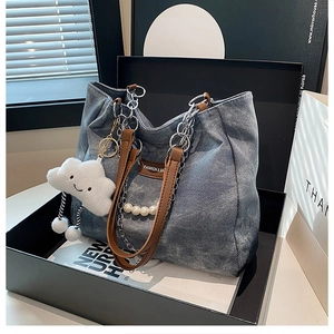 Détail du cabas en denim avec breloque nuage et chaîne de perles en boîte cadeau