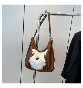 Detail of brown hobo bag with white faux fur animal silhouette and metal hardware