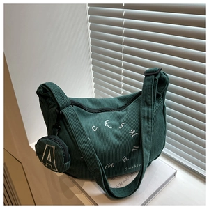 Détail du sac fourre-tout en velours côtelé vert foncé avec petit pendentif et broderie