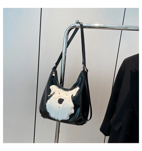 Detail of black patent leather tote bag featuring a white faux fur schnauzer dog motif
