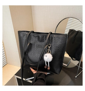 Detail of black houndstooth embossed tote bag with plush monster charm and metal logo