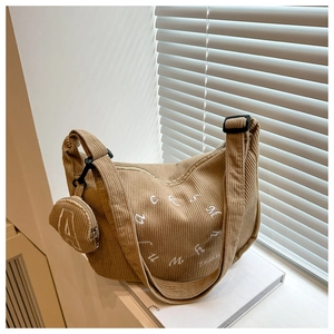 Détail du sac croissant en velours côtelé kaki avec broderie et mini pochette ronde