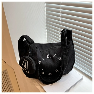 Détail du sac cabas en velours côtelé noir avec broderie blanche et mini pochette ronde