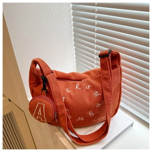 Détail du sac fourre-tout orange en velours côtelé avec mini porte-monnaie et broderie