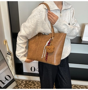 Detail of tan tote bag with soft matte texture featuring a cute plush bear and woven tassel