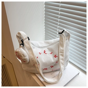 Détail d'un sac cabas en velours côtelé blanc avec broderie rouge et petite pochette