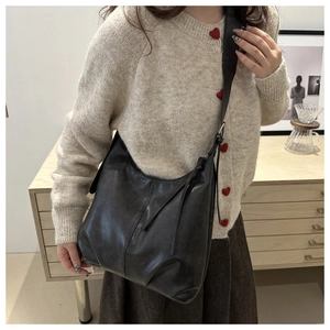 Detail einer schwarzen Hobo-Schultertasche aus mattem Leder mit langem Reißverschluss-Anhänger