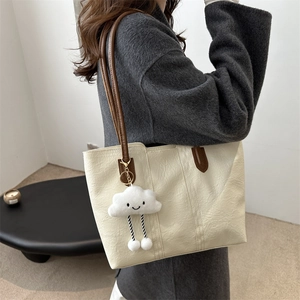 Minimalist beige tote bag with brown straps and cute cloud charm shown in use