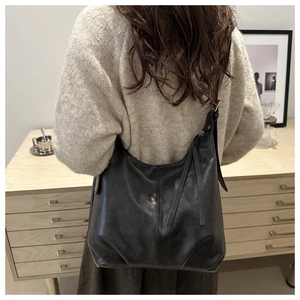 Detail einer großen schwarzen Hobo-Tasche aus Leder mit vertikalen Nähten und verstellbarem Gurt